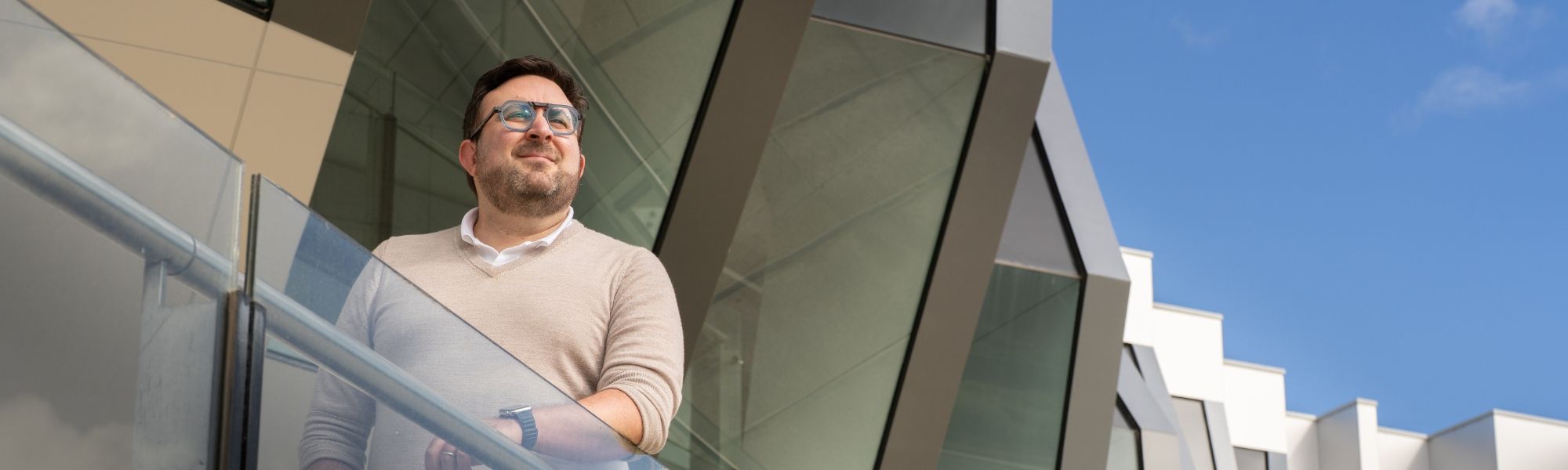 a man standing on a modern balcony with a glass railing